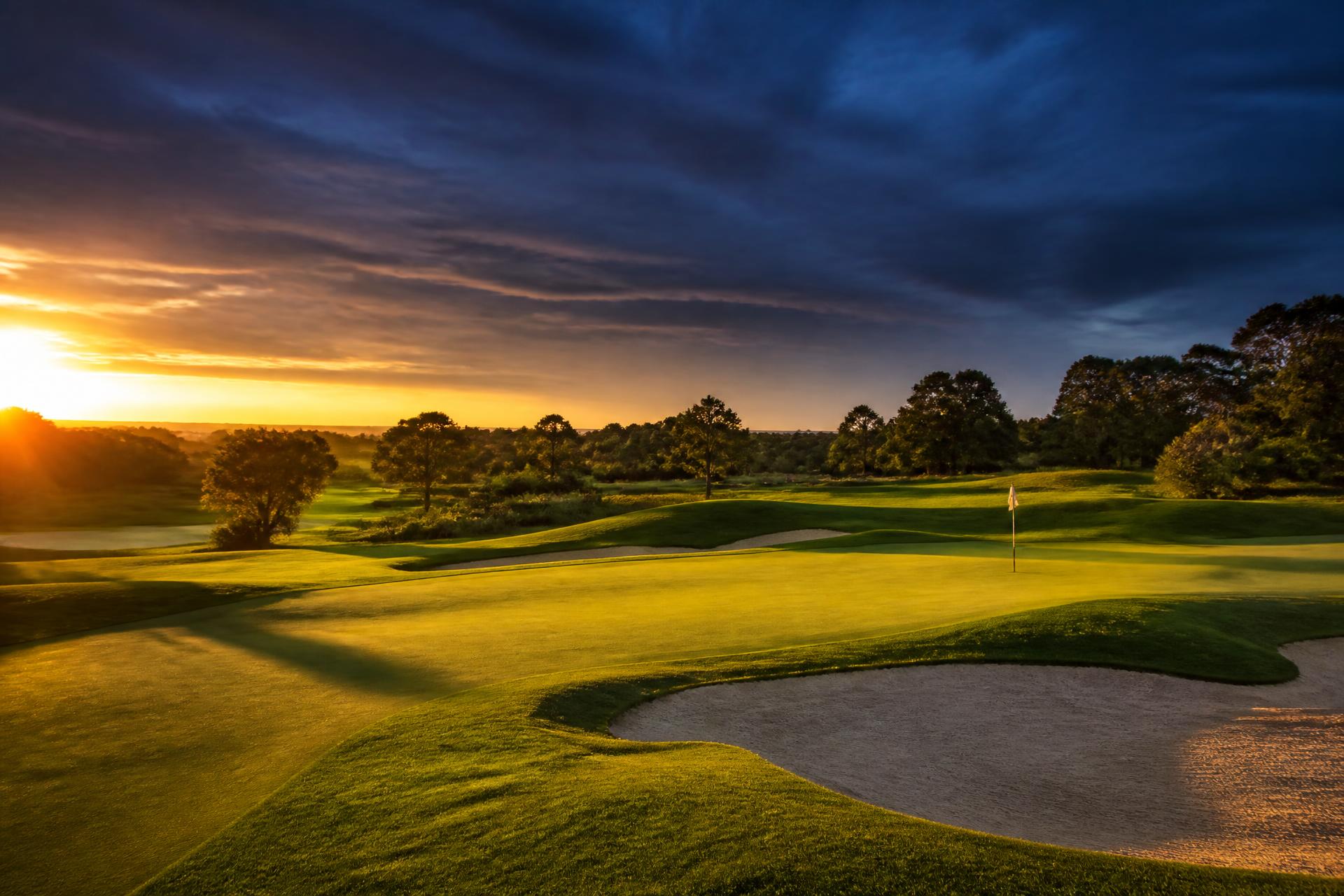 Golfplatz im Abendlicht mit Grün, Bunker und Fahne